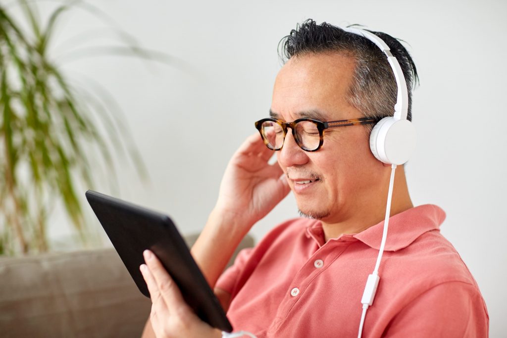 avanco-da-tecnologia-homem-oriental-escutando-pelo-tablet-fone-de-ouvido