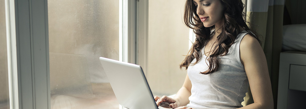 como-conquistar-fieis-na-internet-mulher-sando-notebook-sentada-em-frente-a-janela