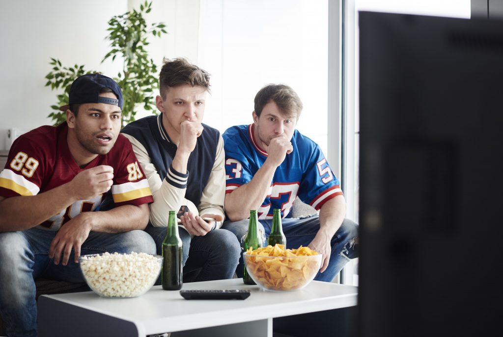 novas-tecnologias-tres-rapazes-assistindo-televisao-apreensivos-esporte