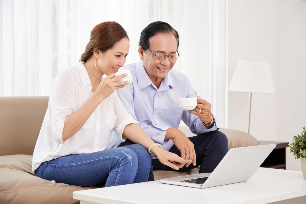homem e mulher de branco assistindo pelo computador