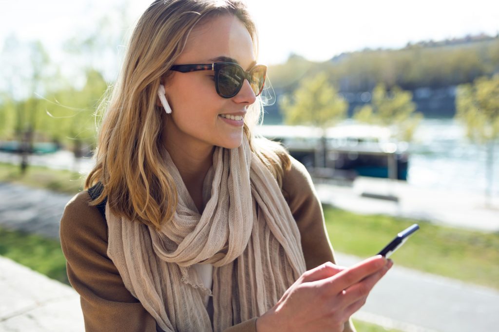 radio-online-mulher-ao-ar-livre-escutando-no-fone-de-ouvido-e-mexendo-no-celular