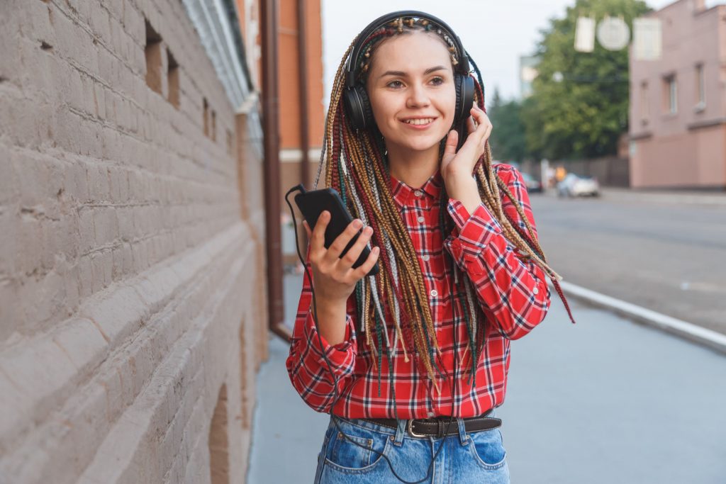 garota-na-rua-escutando-com-fone-de-ouvido-pelo-celular